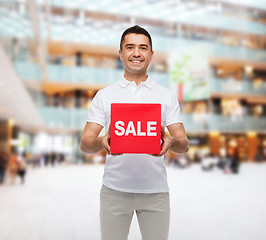 Image showing smiling man with sale sigh over mall background