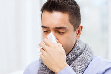 Image showing close up of ill man with flu blowing nose at home