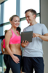 Image showing smiling young woman with personal trainer in gym