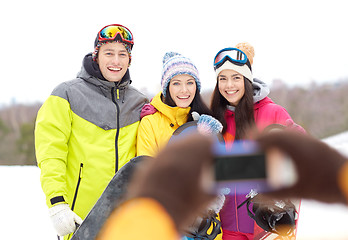 Image showing happy friends with snowboards and smartphone