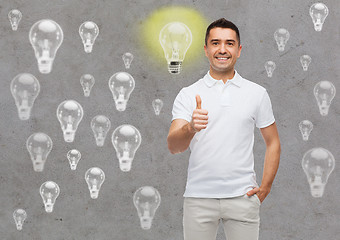 Image showing smiling man showing thumbs up over lighting bulbs