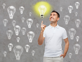 Image showing smiling man pointing finger up to lighting bulb