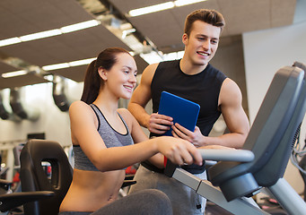 Image showing happy woman with trainer on exercise bike in gym