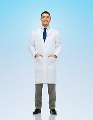 Image showing smiling male doctor in white coat over blue