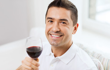 Image showing happy man drinking red wine from glass at home