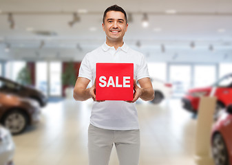Image showing happy man with sale sigh over auto show background