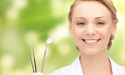 Image showing happy young female dentist with tools