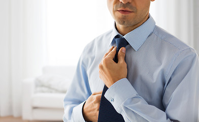 Image showing close up of man in shirt adjusting tie on neck