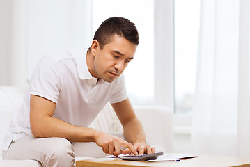 Image showing man with papers and calculator at home