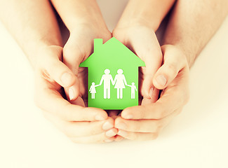 Image showing hands holding green house with family