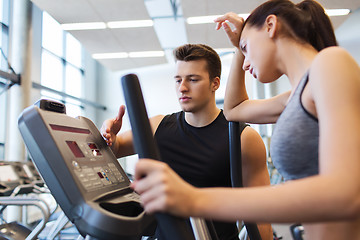 Image showing woman with trainer exercising on stepper in gym