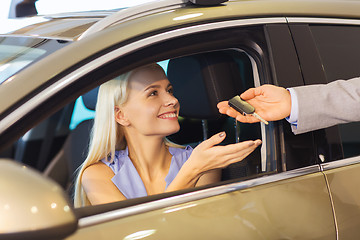 Image showing happy woman getting car key in auto show or salon