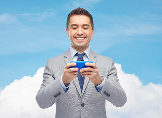 Image showing happy businessman texting on smartphone