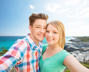 Image showing smiling couple with smartphone on summer beach