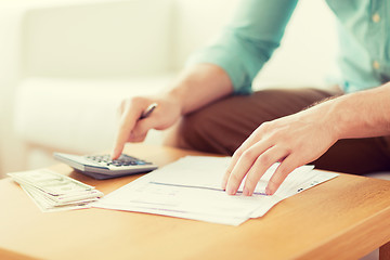 Image showing close up of man counting money and making notes