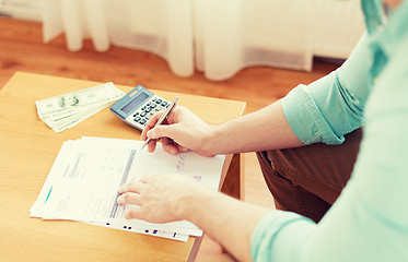 Image showing close up of man counting money and making notes