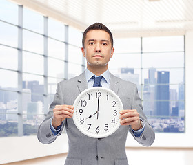 Image showing businessman in suit holding clock with 8 o'clock