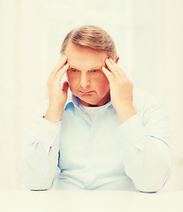 Image showing stressed old man holding head at home