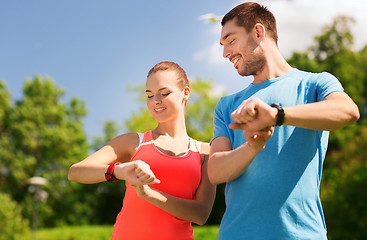 Image showing smiling people with heart rate watches outdoors