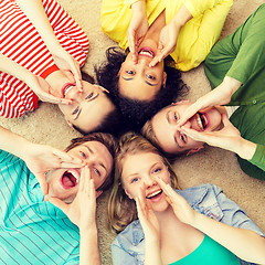 Image showing smiling people lying down on floor and screaming