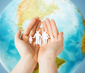 Image showing human hands holding paper family over earth globe