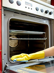 Image showing close up of woman cleaning oven at home kitchen