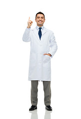 Image showing smiling doctor in white coat pointing finger up