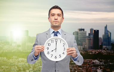 Image showing businessman in suit holding clock with 8 o'clock