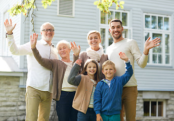 Image showing happy family waving hands in front of house