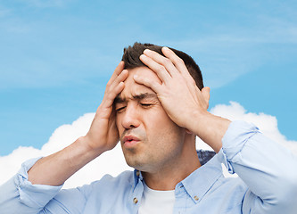 Image showing unhappy man with closed eyes touching his forehead