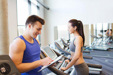 Image showing happy woman with trainer on treadmill in gym