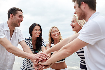 Image showing smiling friends putting hands on top of each other