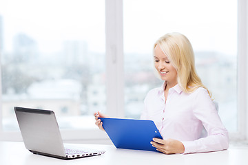 Image showing smiling businesswoman reading papers in office