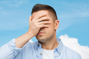 Image showing unhappy man covering his eyes by hand