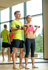 Image showing smiling man and woman with dumbbells in gym