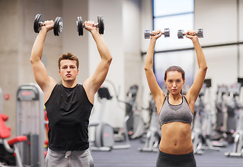 Image showing smiling man and woman with dumbbells in gym