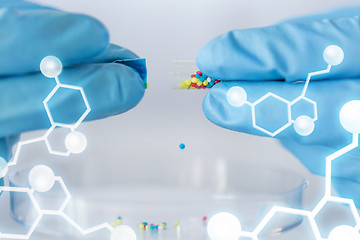 Image showing close up of scientist hands holding pill in lab