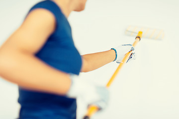 Image showing woman with roller and paint colouring the wall