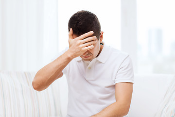 Image showing unhappy man suffering from head ache at home