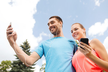 Image showing two smiling people with smartphones outdoors