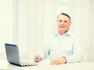 Image showing old man in eyeglasses filling a form at home