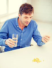 Image showing ill man taking his pills at home