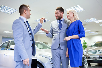 Image showing happy couple with car dealer in auto show or salon