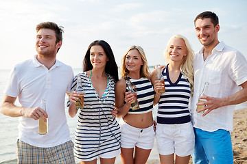 Image showing smiling friends with drinks in bottles on beach