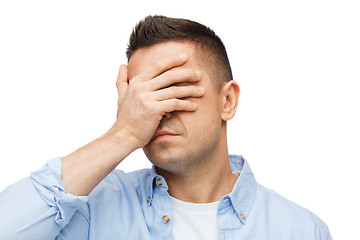 Image showing unhappy man covering his eyes by hand