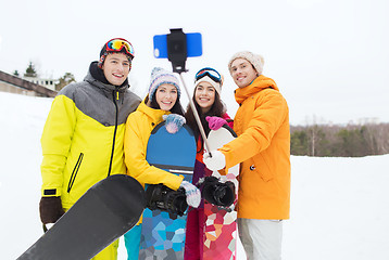 Image showing happy friends with snowboards and smartphone