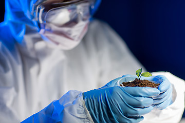 Image showing close up of scientist with plant and soil in lab