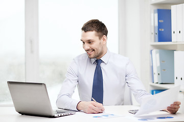 Image showing smiling businessman with laptop and documents