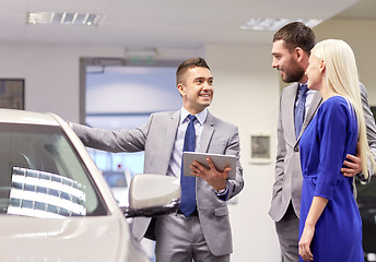 Image showing happy couple with car dealer in auto show or salon