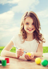 Image showing smiling little girl coloring eggs for easter